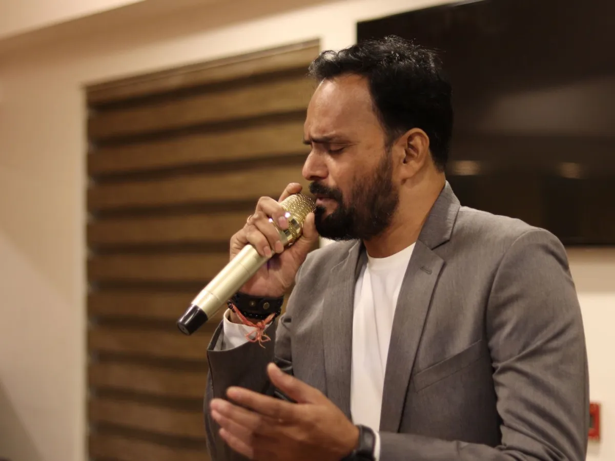 A vocalist singing into a microphone with eyes closed at an intimate indoor performance